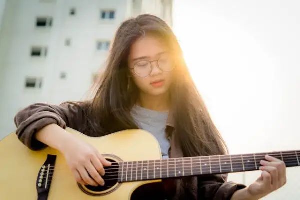 Jovem tocando violão feito de madeira caixeta