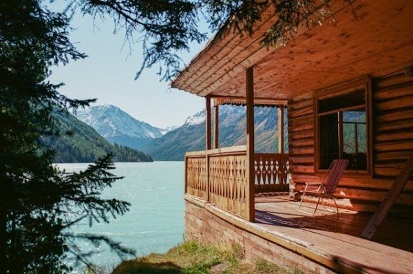 Cabana com paredes e varanda de madeira, a beira do lago